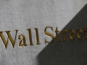 FILE - This March 4, 2013, file photo shows a sign for Wall Street on the side of building near the New York Stock Exchange. Global stock markets traded in narrow ranges Monday, Aug. 21, 2017, as investors awaited a key meeting of central bankers later this week and continued to monitor developments on the Korean peninsula. (AP Photo/Mark Lennihan, File)