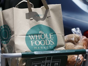 Groceries from Whole Foods Market sit in a cart before being loaded into a car.