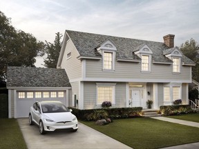 FILE - This file photo provided by Tesla shows a house with Tesla's new slate solar roof tiles. On Thursday, Aug. 31, 2017, Tesla Inc. started production of the cells for its solar roof tiles at its factory in Buffalo, N.Y. The company has already begun installing its solar roofs, which look like regular roofs but are made of glass tiles. Until the Buffalo factory opened, it had been making them on a small scale near its vehicle factory in Fremont, Calif. (Courtesy of Tesla via AP, File)