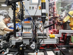 In this Thursday, May 25, 2017 photo, an assembly line laborer works across from a collaborative robot, right, at the Stihl Inc. manufacturing facility in Virginia Beach, Va. At the plant human workers are interspersed with computers and robotics that require trained technicians to service and maintain while reducing the company's need for pursuing traditional manual laborers. (AP Photo/John Minchillo)