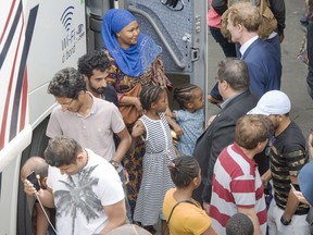 Mayor Denis Coderre, right, greets a busload of asylum seekers at Olympic Stadium on Aug. 3, 2017 in Montreal.The stadium is being used as temporary housing to deal with the influx of asylum seekers arriving from the United States.