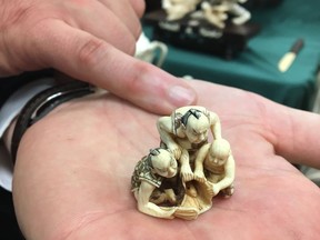 In this July 27, 2017 photo, Lt. Jesse Paluch, the supervising investigator for the state Department of Environmental Conservation in New York City, holds a netsuke carving of 3 men and a fish with a price tag of $14,000, in Albany, N.Y. Nearly two tons of trinkets, statues and jewelry crafted from the tusks of at least 100 slaughtered elephants will be crushed Thursday, Aug. 3 in New York City's Central Park to demonstrate the state's commitment to smashing the illegal ivory trade.  (AP Photo/Mary Esch)