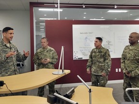 In this Tuesday, Aug. 8, 2017 photo, Col. Michael McGinley, left, gives a tour of the U.S. Defense Department's Defense Innovation Unit Experimental office in Cambridge, Mass., which he oversees. Visiting the office are Maj. Gen. James Young Jr., second from left, of the Army Reserve's 75th Training Command in Houston, and Army Reserve Chief Warrant Officer Pat Nelligan, second from right, who hails from Bristol, Conn. Col. Joseph D'costa, far right, also works at the DIUx office. DIUx works with contractors to fund and develop solutions for the military's toughest technology challenges. (AP Photo/Philip Marcelo)
