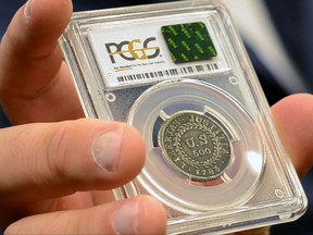 In this Monday, July 31, 2017, image made from a video, David McCarthy, a senior numismatist at Kagin's, holds what is believed to be the first coin ever struck by the U.S. government at the World's Fair of Money in Denver, Colo. The coin is on display this week at the World's Fair of Money in Denver. (AP Photo/Tatiana Flowers)