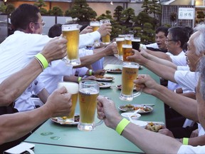 In this Monday, July 31, 2017, photo, office workers raise their beers together for a kanpai, or a toast, at a beer garden on the rooftops of Mitsukoshi department store in Tokyo.  Japan's beer consumption has been tanking as younger "salaryman" types shun old-style after-work drinking and craft breweries woo those who still love their suds. But beer makers are fighting back, striking deals with well-known foreign brands and sprucing up their advertising to reach younger drinkers. (AP Photo/Koji Sasahara)
