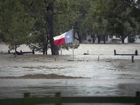 A Texas flag flies over floodwaters caused by Tropical Storm Harvey in La Grange, Texas, Monday, Aug. 28, 2017. (Ralph Barrera/Austin American-Statesman via AP)