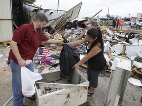 FILE - In this Saturday, Aug. 26, 2017, file photo, Kenneth Bryant and his wife, Jennifer Bryant, search through debris from their business, Bryant's Auto Sales, in Katy, Texas, looking for car keys and paperwork after a tornado spawned by Hurricane Harvey picked up their office and slammed it into the building next door. Harvey's winds and rains have damaged or destroyed many small businesses in the storm's path along the Gulf Coast, and left others in limbo. (Melissa Phillip/Houston Chronicle via AP, File)