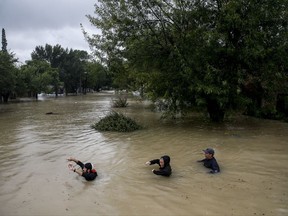 People wade through chest deep water down Pine Cliff Drive as Addicks Reservoir nears capacity due to near constant rain from Tropical Storm Harvey, Tuesday, Aug. 29, 2017 in Houston. (Michael Ciaglo/Houston Chronicle via AP)