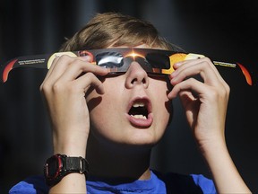 In this Wednesday, Aug. 16, 2017 photo, Colton Hammer tries out his new eclipse glasses he just bought from the Clark Planetarium in Salt Lake City in preparation for the eclipse. (Scott G Winterton/The Deseret News via AP)