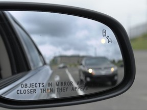 FILE - In his May 22, 2012 file photo, a side mirror warning signal in a Ford Taurus at an automobile testing area in Oxon Hill, Md. Safety systems to prevent cars from drifting into another lane or warn drivers of vehicles in their blind spots are beginning to live up to their potential to significantly reduce crashes, according to two studies released Wednesday, Aug. 23, 2017.  (AP Photo/Susan Walsh, File)