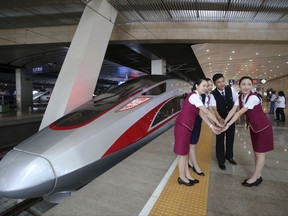 FILE - In this June 26, 2017 file photo, railway workers pose for photos with the Fuxing, China's latest high speed train capable of reaching 400kph (248mph) during its maiden service from Beijing. China is relaunching the world's fastest bullet trains in September 2017, running at 350 kilometers (217 miles) per hour. China first ran trains at 350 kilometers per hour in August 2008, but cut speeds back to 250-300 kilometer per hour in 2011 following a two-train collision near the city of Wenzhou that killed 40 people and injured 191. (Chinatopix Via AP, File)