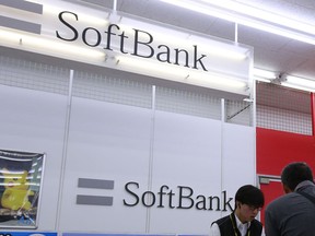 A shopper, right, and a clerk talk at a SoftBank sales counter at a store in Tokyo, Monday, Aug. 7, 2017. Japanese technology company SoftBank Group Corp. has reported a 98 percent drop in its April-June profit on losses stemming from investments in the Chinese e-commerce company Alibaba. (AP Photo/Shizuo Kambayashi)
