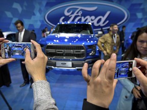 In this April 23, 2016, photo, attendees take smartphone photos at a promotional event for Ford Motor Company ahead of the Auto China car show in Beijing. Ford Motor Co. announced an agreement Tuesday, Aug. 22, 2017 with a Chinese partner to look into forming a joint venture to develop and manufacture electric cars in China. (AP Photo/Mark Schiefelbein)