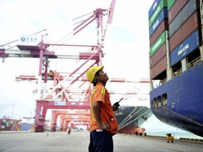 In this Tuesday, Aug. 8, 2017 photo, a worker watches as shipping containers are loaded onto a ship at a port in Qingdao in eastern China's Shandong province. China's government says it will respond to a possible trade probe ordered by President Donald Trump with "all appropriate measures" to protect Chinese interests. (Chinatopix via AP)