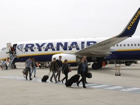FILE  - In this Wednesday, May 13, 2015 file photo, passengers disembark a Ryanair plane, at the Marseille Provence airport, in Marignane, southern France.  Budget airline Ryanair is reducing its fleet and cancelling thousands of more flights as it struggles to overcome a pilot scheduling crisis. (AP Photo/Claude Paris, FIle)