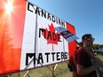 Unifor workers picket in the shade of a huge Canadian flag erected at the entrance at Cami in Ingersol on a warm Friday afternoon on Friday September 22, 2017.