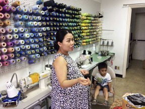 In this Sept. 2, 2017 photo, Maria Tran, co-owners of Chic Tailors, near Brays Bayou in Meyerland, Texas, prepares to open her business with her 3-year-old son, Ander. Tran wants to get the shop open quickly so her sister can take over while she gives birth to her second child, a daughter. She worries because she watched customers move away after previous floods. But for now she says she has "no complaints. Compared with other people, we're lucky we're still here and alive.'' (AP Photo/Brian Melley)