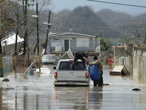 Residents evacuate after the passing of Hurricane Maria, in Toa Baja, Puerto Rico, Friday, September 22, 2017. Because of the heavy rains brought by Maria, thousands of people were evacuated from Toa Baja after the municipal government opened the gates of the Rio La Plata Dam. (AP Photo/Carlos Giusti)