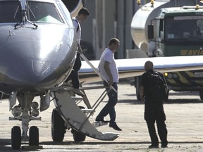 Joesley Batista, former chairman of JBS meatpacking giant, center, arrives at the airport during his transfer to a federal police jail after he turned himself in to authorities, in Brasilia, Brazil, Monday, Sept. 11, 2017. Brazilian police are searching the homes of former and current executives of the world's largest meatpacker whose plea bargain testimony has implicated the president in corruption. (AP Photo/Eraldo Peres)