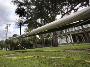 FILE - In this Monday, Sept. 18, 2017, file photo, a week after Hurricane Irma hit central Florida, a cable belonging to Spectrum/Charter Communications remains just a few inches off the ground in a Maitland, Fla. neighborhood. The power's back on in Florida, but the internet is lagging. Many homes get internet service back once power is restored, but that's not true for everyone. (Joe Burbank /Orlando Sentinel via AP, File)