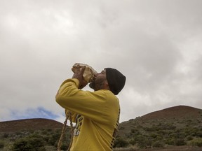 FILE - In this Aug. 31, 2015 file photo, Kupono Mele-Ana-Kekua, 35, of Kaaaawa, Hawaii, blows a conch shell near the summit of Mauna Kea on Hawaii's Big Island. Mele-Ana-Kekua had camped on the mountain for about 60 days in protest of the Thirty Meter Telescope. Hawaii's land board on Thursday, Sept. 28, 2017 granted a construction permit for a giant telescope on a mountain that Native Hawaiians consider sacred, a project that has divided the state. The $1.4 billion Thirty Meter Telescope has pitted people who say the instrument will provide educational and economic opportunities against those who say it will desecrate the state's tallest mountain, called Mauna Kea. (AP Photo/Caleb Jones, File)