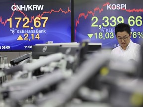 A currency trader talks near screens showing the Korea Composite Stock Price Index (KOSPI), right, and the foreign exchange rate at the foreign exchange dealing room in Seoul, South Korea, Monday, Sept. 4, 2017. Asian shares were mostly lower Monday, on investor jitters shaken up by a North Korean nuclear test over the weekend that raised fears about risks to regional stability. (AP Photo/Lee Jin-man)