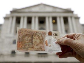 One of the new British 10 pound notes is posed for photographs outside the Bank of England in the City of London, Thursday, Sept. 14, 2017. The new polymer note, released for circulation on Thursday, features the renowned novelist Jane Austen and is the first UK banknote with a tactile feature to support blind and partially sighted users. (AP Photo/Matt Dunham)