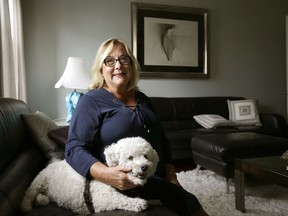 In this Wednesday, Sept. 13, 2017 photo Airbnb operator Jennifer McConnell sits for a photograph with her 10-year-old bichon dog "Skipper," in a communal area of her home, in Cambridge, Mass. College towns like Cambridge say they are feeling the pinch in the debate over whether short term rental sites like Airbnb have driven up housing costs. Cambridge, home to Harvard University and the Massachusetts Institute of Technology, has approved new regulations requiring those offering short term rentals to live in the same building and undergo an inspection once every five years. McConnell said she's okay with the city's regulations but isn't thrilled about the inspections. She said she also doesn't fault Airbnb for the city's soaring housing and rental costs. (AP Photo/Steven Senne)