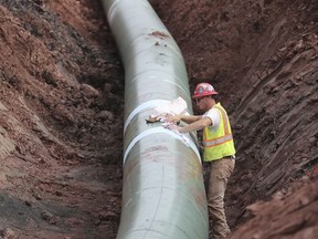 In an Aug. 21, 2017 photo, a pipe fitter lays the finish finishing touches to the replacement of Line 3 stretch before it is covered up. Enbridge already has started building the 14-mile stretch of Line 3 from the Minnesota line to its terminal in Superior, Wis. In filings with the Public Utilities Commission Monday, Sept. 11, The Minnesota Department of Commerce says Enbridge Energy has failed to establish the need for its proposal to replace its aging Line 3 crude oil pipeline across northern Minnesota. Instead, the department says it might be better to just shut down the existing line.  (Richard Tsong-Taatarii/Star Tribune via AP)