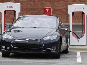FILE - In this Saturday, June 24, 2017, file photo, a Tesla car recharges at a charging station at Cochran Commons shopping center in Charlotte, N.C. On Monday, Sept. 11, 2017, Tesla Inc. announced that more charging stations are on the way. The stations will be installed at places such as supermarkets and shopping centers, and in cities like Chicago and Boston. (AP Photo/Chuck Burton, File)