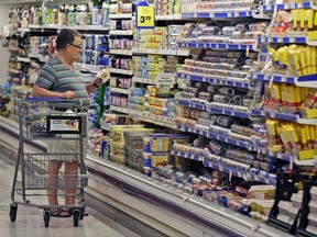 FILE - In this June 17, 2014, file photo, a shopper looks at an item in the dairy section of a Kroger grocery store in Richardson, Texas. Some of the world's biggest consumer goods companies have agreed to simplify food date labels that create confusion among shoppers and leads them to discard billions of dollars' worth of food. The goal: to streamline the labels, including "Sell by" and "Display Until," down to two by 2020, says The Consumer Goods Forum. (AP Photo/LM Otero, File)