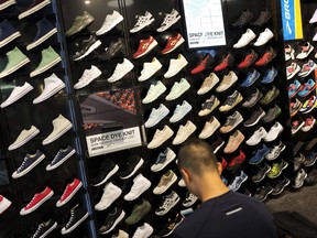 In this Tuesday, Aug. 22, 2017, photo, a customer looks at shoes at a Foot Locker in New York. On Friday, Sept. 15, 2017, the Commerce Department reports on business stockpiles in July. (AP Photo/Mark Lennihan)