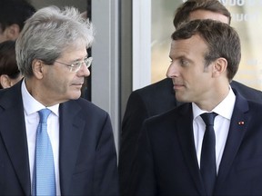 French President Emmanuel Macron and Italian Prime Minister Paolo Gentiloni, left, arrive at the Confluences Museum in Lyon, central France, before visiting the "Lumiere ! l'Invention du Cinema" exhibition within the 34th French - Italian summit in Lyon, Wednesday, Sept. 27, 2017. The French and Italian governments are expected to announce Wednesday a deal allowing Italian shipbuilder Fincantieri to take control of a key French shipyard, ending a weeks-long disagreement between the countries. (Ludovic Marin/Pool Photo via AP)