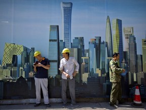 FILE - In this Sept. 22, 2017 file photo, construction workers smoke outside of a construction site in the central business district in Beijing. The Asian Development Bank is raising its growth forecast for Asia's developing economies because global trade and conditions in the world's biggest economies are improving more than expected. The Manila-based lender said Tuesday, Sept. 26, 2017, it now predicts the region's economy will expand 5.9 percent this year and 5.8 percent in 2018. (AP Photo/Mark Schiefelbein, File)