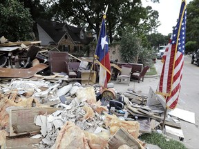 In this Sept. 5, 2017, photo, a worker walks past a pile of debris outside a business damaged by floodwaters in the aftermath of Hurricane Harvey in Spring, Texas. With federal disaster reserves running out, the House is swiftly moving to pass President Donald Trump's request for a $7.9 billion first installment of relief for victims of Harvey. GOP leaders also hope to use the urgent Harvey aid bill to solve a far more vexing issue: Increasing the U.S. debt limit to permit the government to borrow freely again to cover its bills.  (AP Photo/David J. Phillip)