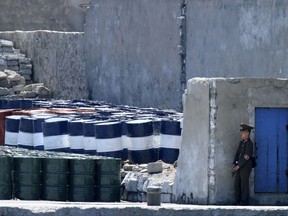 FILE - In this May 8, 2016, file photo, a North Korean solder stands guard near barrels stacked up near the river bank of the North Korean town of Sinuiju, opposite the Chinese border city of Dandong. China announced Saturday, Sept. 23, 2017 it will limit oil supplies to North Korea under U.N. sanctions starting Oct. 1, 2017, stepping up pressure on Pyongyang over its pursuit of nuclear and missile technology. (Chinatopix via AP, File)