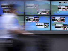 A man rides a bicycle past an electronic stock board showing Japan's Nikkei 225 index and other countries at a securities firm in Tokyo, Tuesday, Sept. 12, 2017. Asian shares were mostly higher Tuesday, encouraged by optimism on Wall Street as Hurricane Irma weakened and made way for recovery efforts and a North Korean holiday passed without new missile launches. (AP Photo/Eugene Hoshiko)