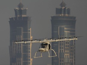 In this Sept. 26, 2017 photo, a Volocopter prototype flies in front of the two hotel towers during a test flight in Dubai, United Arab Emirates. Dubai is hoping to one day have flying, pilotless taxis darting among its skyscrapers. Just this week, the city-state in the United Arab Emirates hosted crews from the German company Volocopter, which had an electric, battery-powered two-seat prototype take off and land. Dubai hopes to have rules in place in the next five years to be ready for having the aircraft regularly flying through its skies. (AP Photo/Kamran Jebreili)