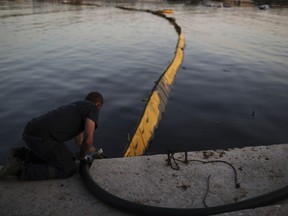 A worker from a cleaning company uses a hose to suck up polluted water from an oil spillage in front of a floating boom in Glyfada, suburb of Athens, on Monday, Sept. 18, 2017. The World Wildlife Fund has filed a lawsuit in Greece over extensive pollution along Athens' coastline following the sinking of a tanker near the country's largest port of Piraeus..(AP Photo/Petros Giannakouris)