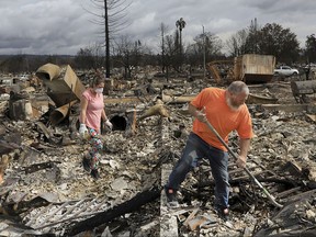 Sarah Boryszewski is helped by her father Gerald Peete as they dig for belongings in the remains of Boryszewski's home in Coffey Park, Friday Oct. 20, 2017 in Santa Rosa, Calif. Northern California residents who fled a wildfire in the dead of night with only minutes to spare returned to their neighborhoods Friday for the first time in nearly two weeks to see if anything was standing. (Kent Porter/The Press Democrat via AP)