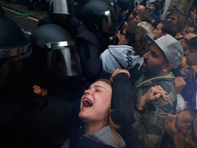 A girl grimaces as Spanish National Police push away Pro-referendum supporters outside a polling station in Barcelona, Spain.