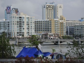 In this Oct. 23, 2017 photo, tents stand on the other side of the shore of Laguna de Condado opposite the exclusive area of ​​Paseo Caribe in San Juan, Puerto Rico. Hurricane Maria didn't discriminate between rich and poor when it ravaged Puerto Rico, but the recovery has been another story. (AP Photo/Carlos Giusti)