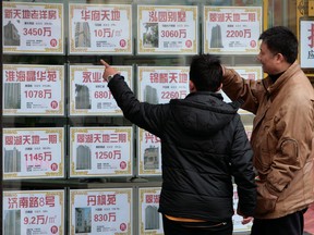 Two people look in a real estate agents window in Shanghai, China.