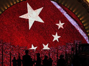 Visitors is silhouetted as they watch a video display boards showing the Chinese flag at an exhibition highlighting China's achievements under five years of leadership by Chinese President Xi Jinping at the Beijing Exhibition Hall in the capital city where the 19th Party Congress is held in Beijing, Monday, Oct. 23.