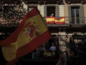 People stay on their balconies decorated with Spanish flags during a mass rally against Catalonia's declaration of independence, in Barcelona, Spain, Sunday, Oct. 29, 2017. Thousands of opponents of independence for Catalonia are holding the rally on one of the city's main avenues after one of the country's most tumultuous days in decades. (AP Photo/Gonzalo Arroyo)