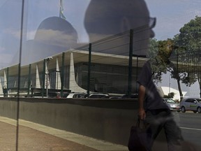Planalto presidential palace is reflected in the window of a bus stop in Brasilia, Brazil, Tuesday, Oct. 24, 2017. Brazil's lower chamber of Congress is preparing to vote on Wednesday on whether to try President Michel Temer on charges of leading a criminal organization and obstructing justice, the second time Temer will face such a vote. (AP Photo/Eraldo Peres)