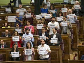 Lawmakers hold up posters reading: "Free Jordi Sanchez and Jordi Cuixart," leaders of the Catalan grassroots organizations Catalan National Assembly and Omnium Cultural, during a parliamentary session at the Spanish parliament in Madrid, Wednesday, Oct. 18, 2017. About 50 Spanish and Catalan party lawmakers held up posters in the parliament demanding the release of two pro-Catalonia independence movement leaders, describing them as political prisoners. (AP Photo/Francisco Seco)