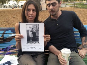 File - In this Oct. 13, 2017 file photo, Chrystal Couto holds a poster of her then missing grandmother, who was later found alive, as Aaron Austin looks on in Santa Rosa, Calif. The deadliest and most destructive series of wildfires in California history burned thousands of buildings and sent tens of thousands of people fleeing their homes, but the death toll is likely to remain relatively low. Only 42 bodies have been found more than a week after wildfires started, a surprising figure given that complete neighborhoods were wiped out in the dead of night and hundreds of people were initially reported as missing. (AP Photo/Paul Elias, File)