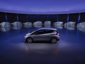 A Chevrolet Bolt is displayed, surrounded by nine electric and fuel cell vehicles covered by tarps.