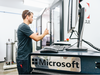 A Microsoft employee loads a slate of magnesium into a water-jet cutting machine for a hardware prototype.